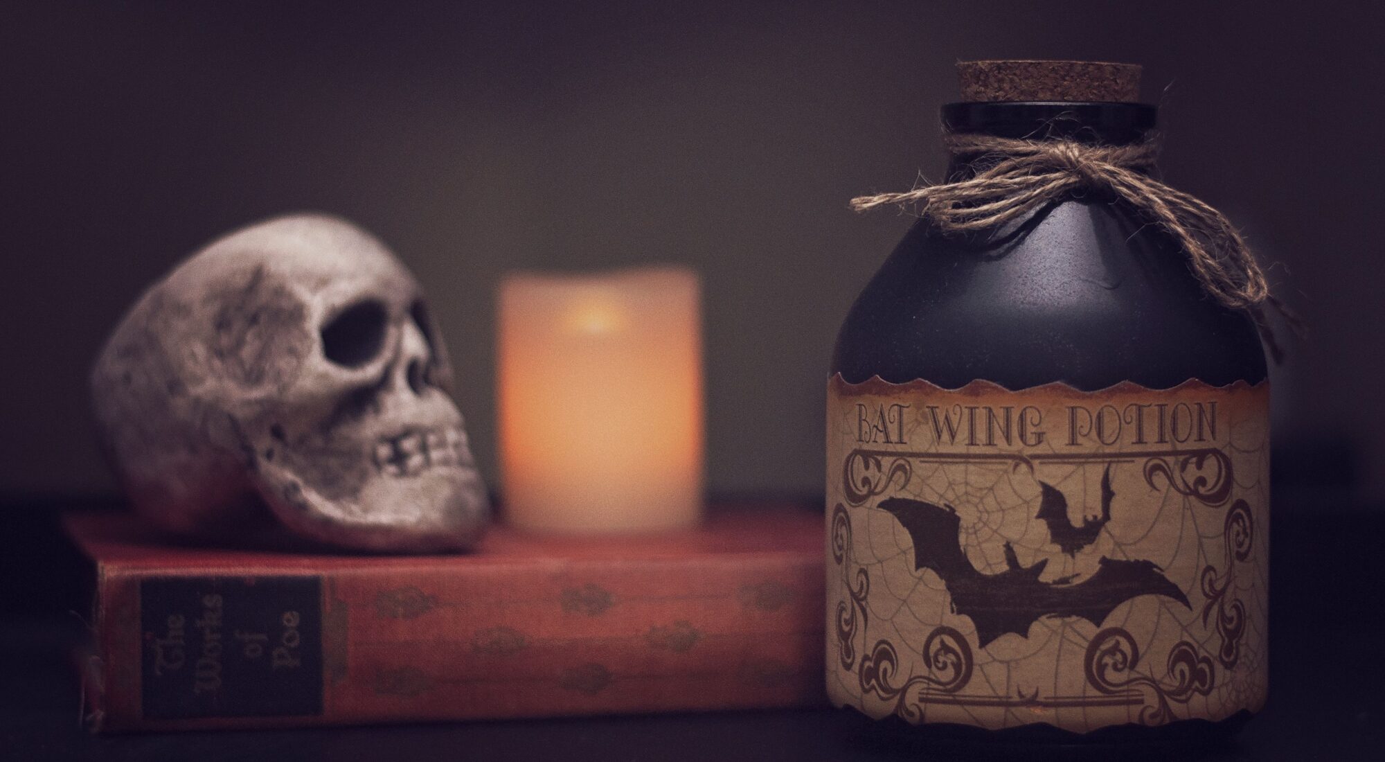 Halloweenatmosphäre mit Kerze, altem Buch und Schädel